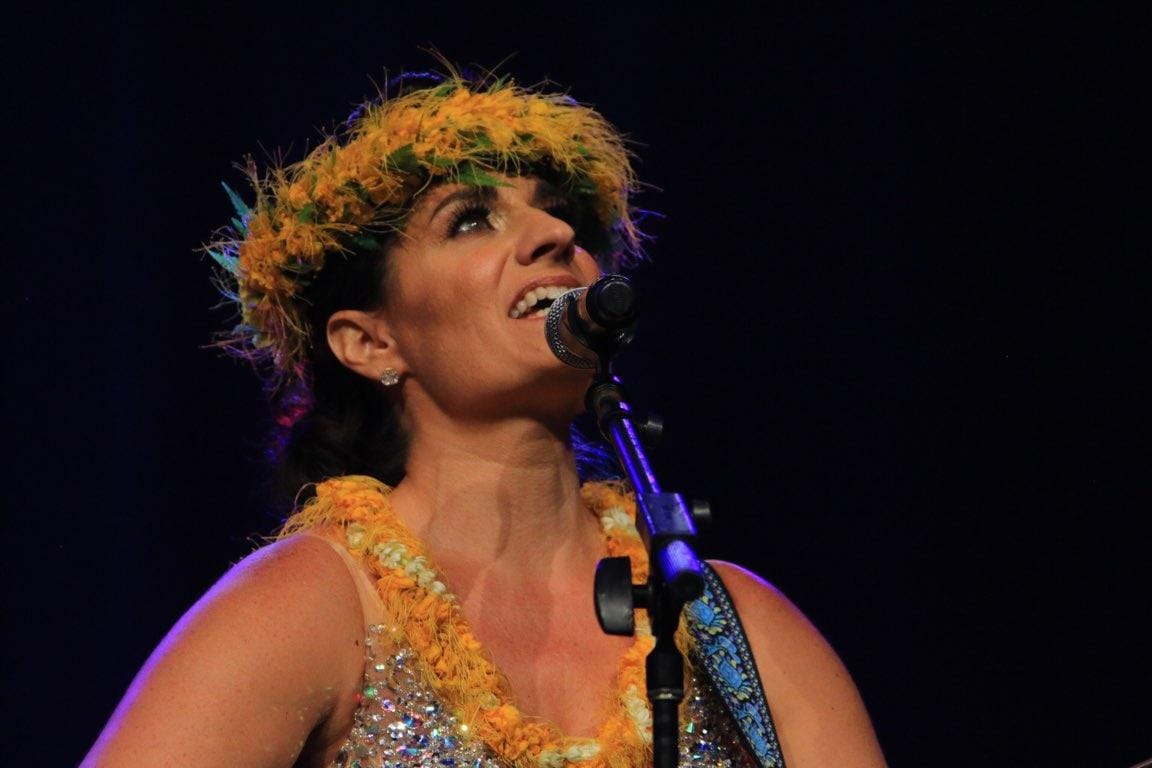 Stef Mariani performing live on stage wearing a haku lei